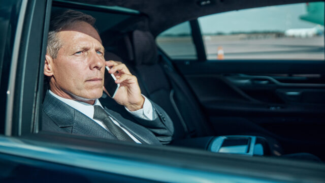 Businessman talking on cell phone in luxury automobile